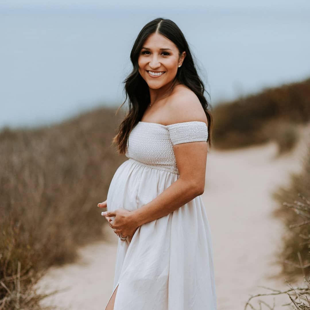 Pregnant mother, smiling and holding her baby on the beach